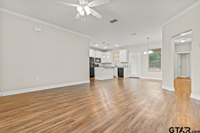 unfurnished living room featuring ornamental molding, light hardwood / wood-style floors, and ceiling fan with notable chandelier