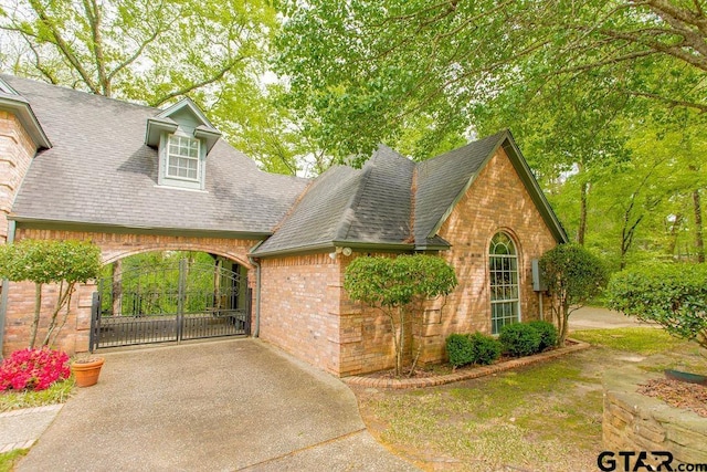 view of front facade with brick siding and roof with shingles