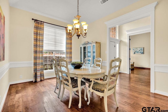 dining space with baseboards, an inviting chandelier, wood finished floors, and visible vents