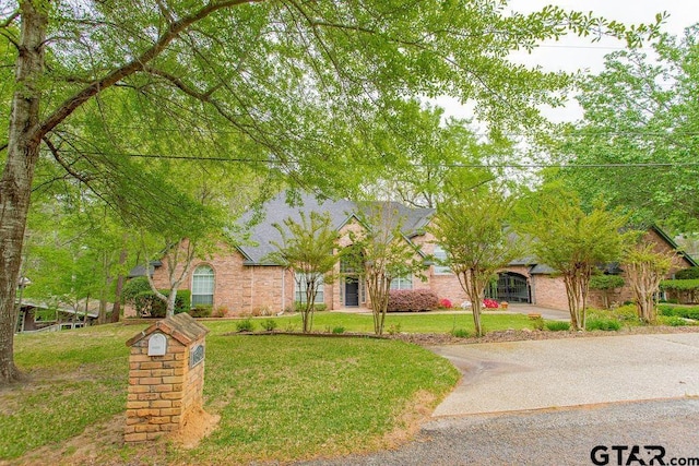 obstructed view of property featuring brick siding and a front yard