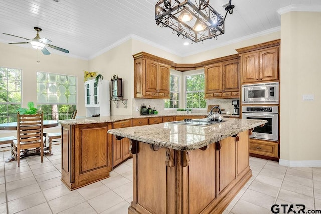 kitchen featuring a center island, light stone countertops, brown cabinets, a breakfast bar, and stainless steel appliances