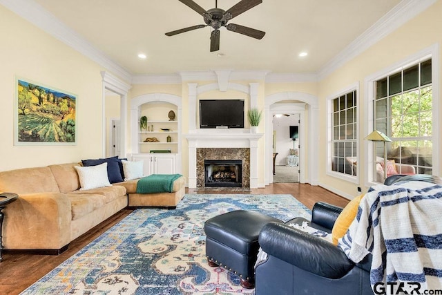 living area featuring arched walkways, ceiling fan, ornamental molding, and wood finished floors