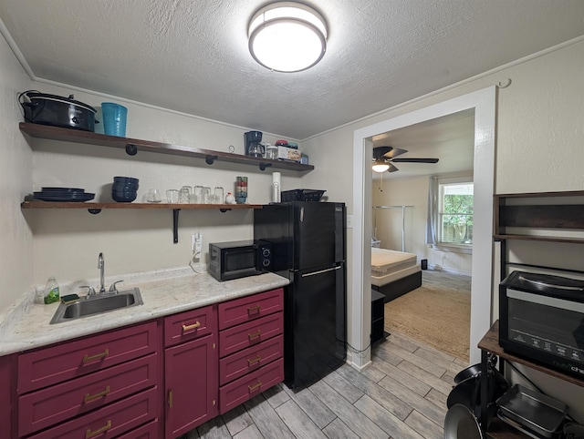 601 Troup Hwy, Tyler, TX 75701 - kitchen with black appliances, light wood-style flooring, red cabinets, light countertops, and a textured ceiling
