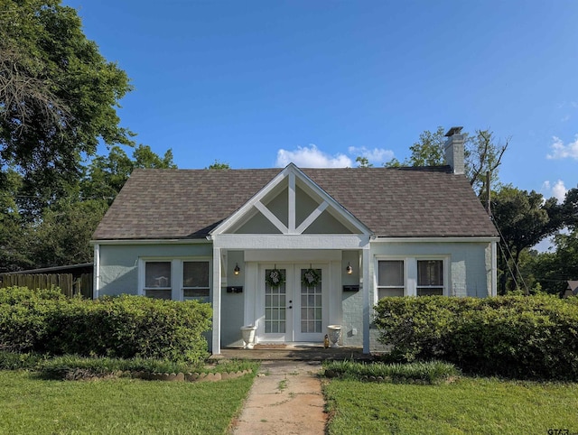 601 Troup Hwy, Tyler, TX 75701 - view of front of property with french doors, a shingled roof, a chimney, and a front lawn