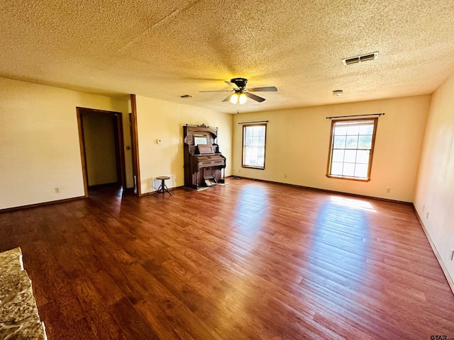 unfurnished room with a ceiling fan, wood finished floors, visible vents, and baseboards