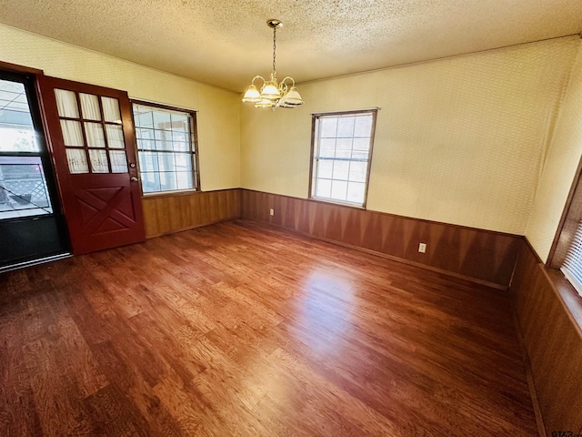 unfurnished room with wallpapered walls, wood finished floors, a wainscoted wall, and a textured ceiling