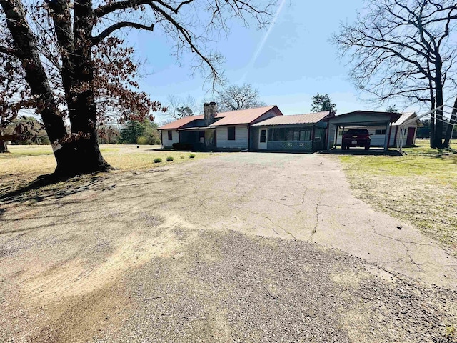 single story home with aphalt driveway, a front lawn, and a chimney