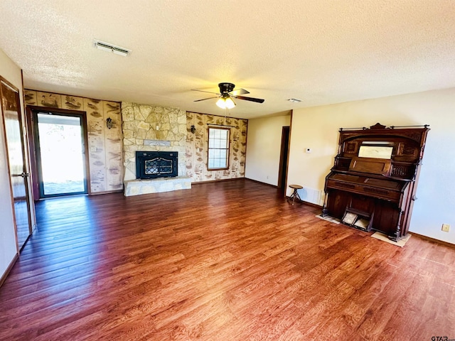 unfurnished living room with visible vents, a healthy amount of sunlight, a stone fireplace, and wood finished floors