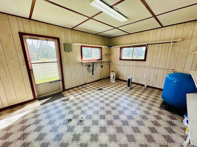 workout area featuring tile patterned floors, wooden walls, and baseboards