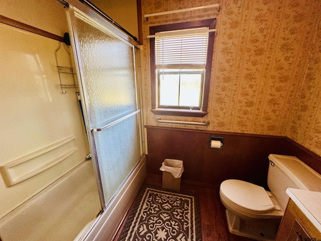 bathroom with vanity, bath / shower combo with glass door, toilet, and wallpapered walls