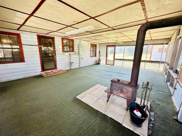 unfurnished sunroom featuring a wood stove