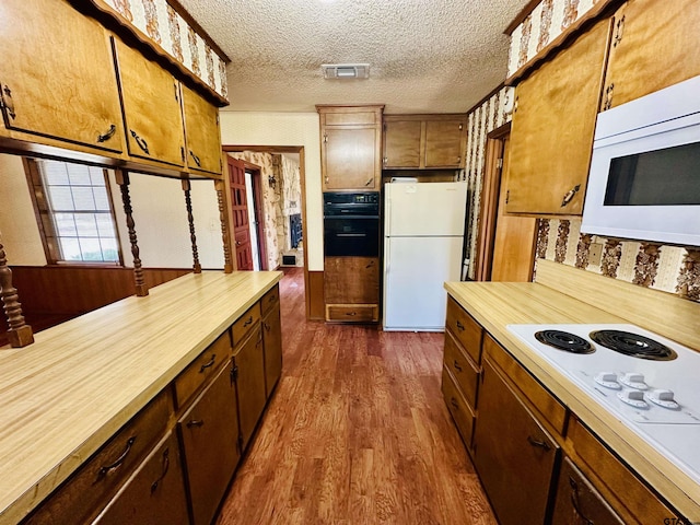 kitchen featuring visible vents, light countertops, dark wood-style floors, white appliances, and a textured ceiling