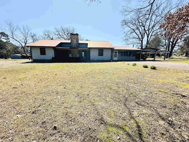 view of front of property featuring metal roof, a front lawn, and a chimney