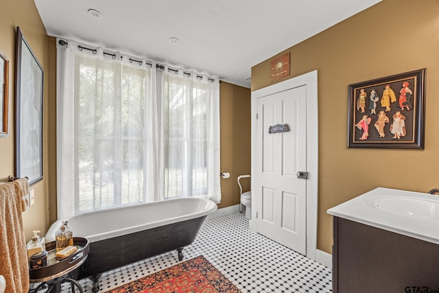 bathroom featuring a wealth of natural light, vanity, toilet, and a bath