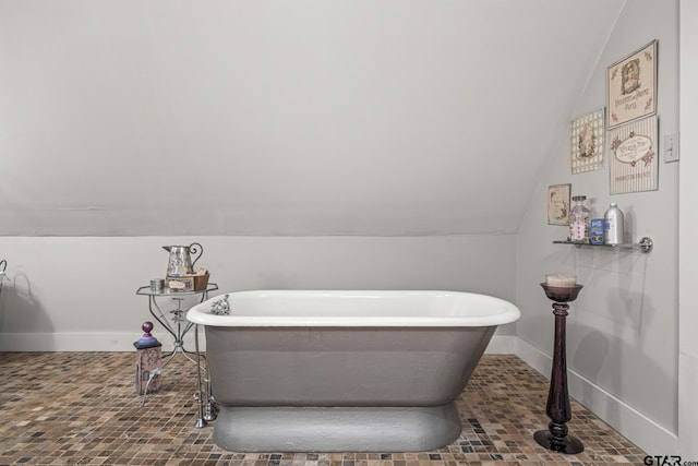 bathroom featuring a tub to relax in and lofted ceiling