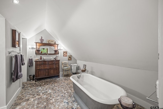 bathroom featuring vanity, lofted ceiling, and a bathing tub