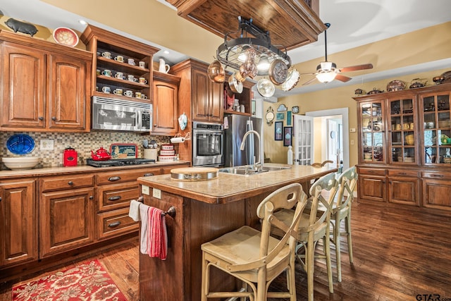 kitchen featuring stainless steel appliances, sink, a breakfast bar, an island with sink, and dark wood-type flooring