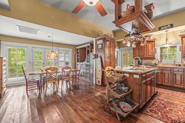 kitchen with a center island with sink, sink, ceiling fan, dark hardwood / wood-style floors, and backsplash