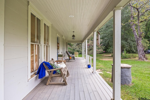 wooden terrace with a lawn and a porch