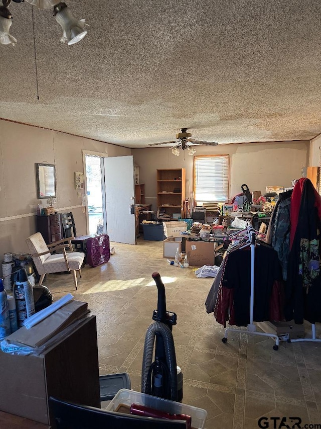 living area featuring ceiling fan and a textured ceiling