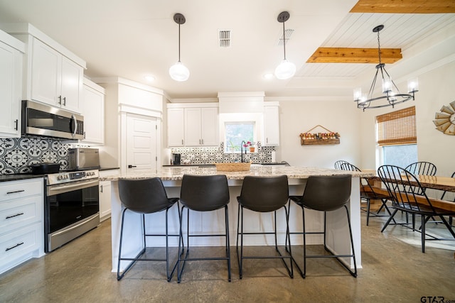 kitchen featuring white cabinets, decorative light fixtures, a center island, and stainless steel appliances