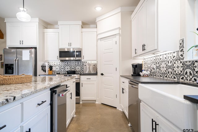 kitchen with white cabinetry, hanging light fixtures, appliances with stainless steel finishes, and dark stone counters