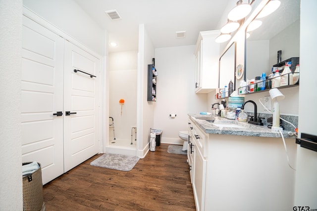 bathroom featuring a shower, hardwood / wood-style floors, vanity, and toilet