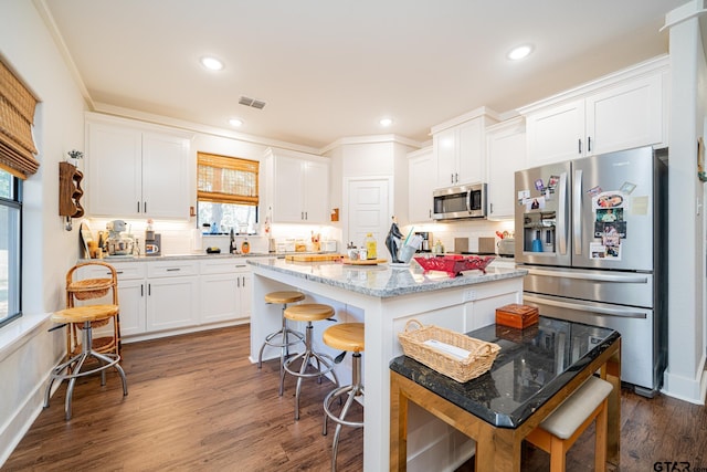 kitchen with light stone countertops, a center island, stainless steel appliances, dark hardwood / wood-style floors, and white cabinets