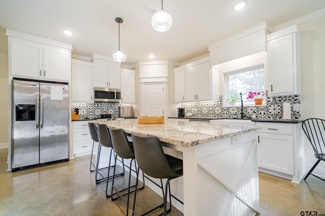 kitchen with white cabinets, decorative light fixtures, stainless steel appliances, and a kitchen island