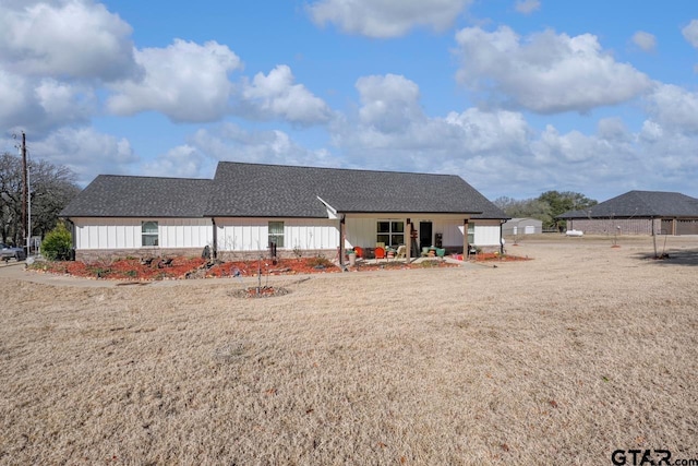 view of front facade with a shingled roof and a front yard