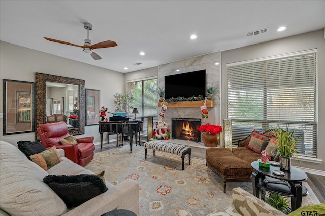 living room featuring ceiling fan, wood-type flooring, and a high end fireplace