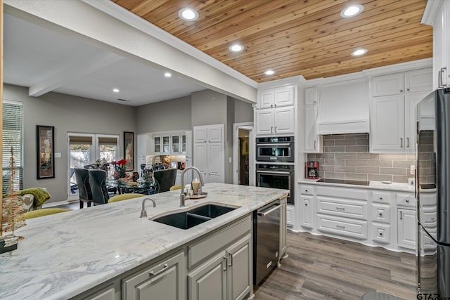 kitchen with sink, tasteful backsplash, white cabinetry, wood-type flooring, and stainless steel appliances