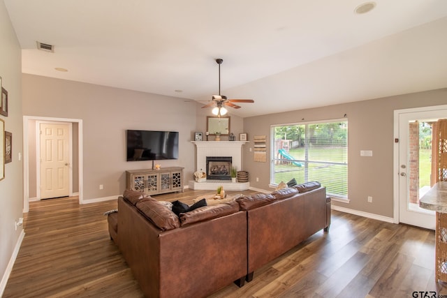 living room featuring dark wood-type flooring, a fireplace, ceiling fan, and vaulted ceiling