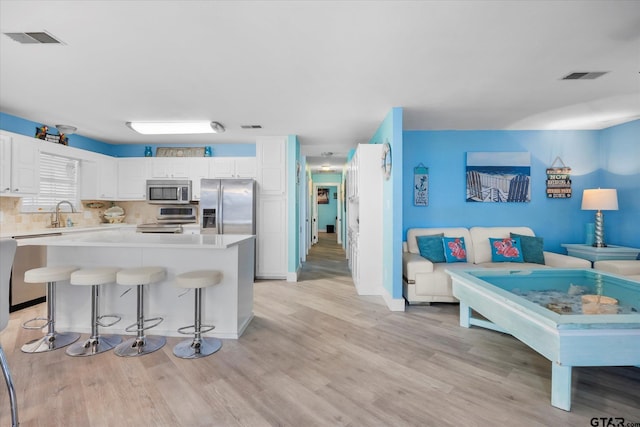 220 Pin Oak Dr, Mabank, TX 75156 - kitchen with appliances with stainless steel finishes, light wood-style floors, light countertops, white cabinetry, and a kitchen breakfast bar