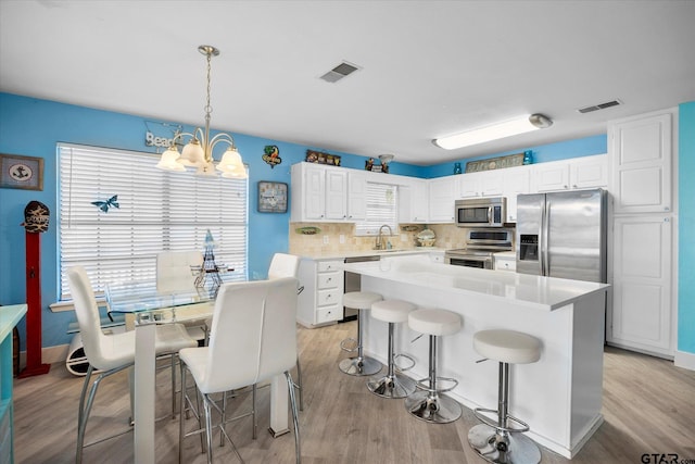 220 Pin Oak Dr, Mabank, TX 75156 - kitchen featuring stainless steel appliances, a chandelier, white cabinetry, a kitchen bar, and light countertops