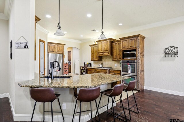 3449 Abes Landing Dr, Granbury, TX 76049 - kitchen with brown cabinetry, a peninsula, a breakfast bar area, appliances with stainless steel finishes, and recessed lighting