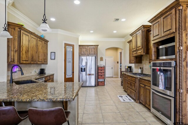 3449 Abes Landing Dr, Granbury, TX 76049 - kitchen featuring appliances with stainless steel finishes, a peninsula, decorative backsplash, arched walkways, and ornamental molding