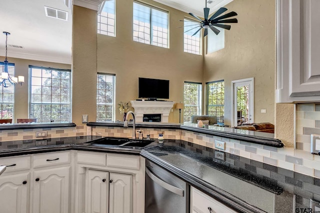 kitchen with sink, crown molding, hanging light fixtures, white cabinets, and stainless steel dishwasher