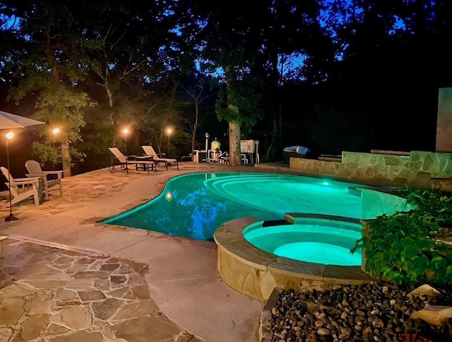 pool at twilight featuring an in ground hot tub and a patio area