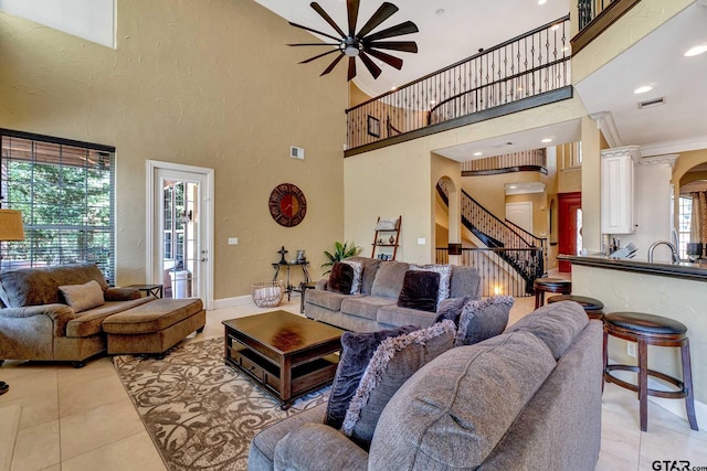 tiled living room featuring a towering ceiling, sink, and ceiling fan