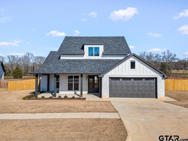 modern farmhouse style home featuring a shingled roof, brick siding, fence, concrete driveway, and board and batten siding