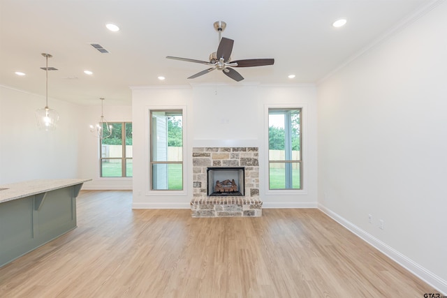 unfurnished living room featuring crown molding, a fireplace, light hardwood / wood-style floors, and ceiling fan with notable chandelier