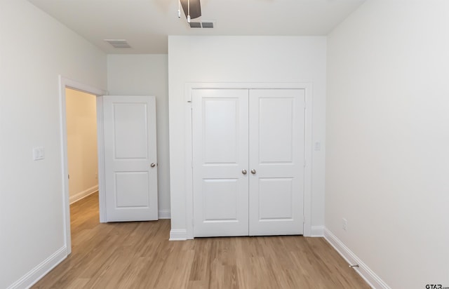 unfurnished bedroom featuring ceiling fan, a closet, and light wood-type flooring