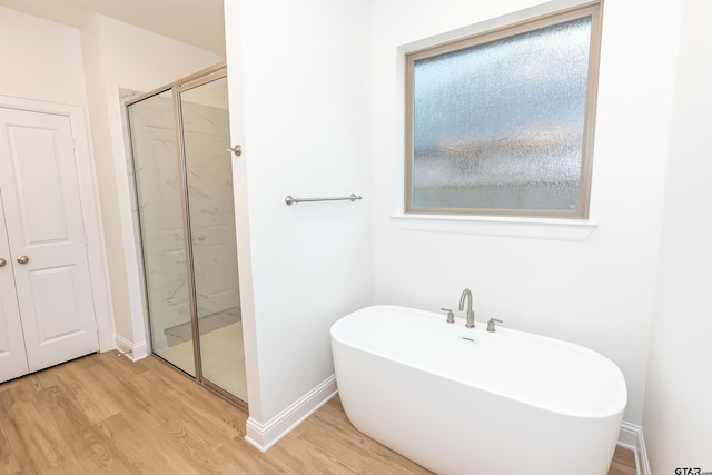 bathroom with hardwood / wood-style flooring and independent shower and bath