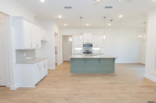 kitchen featuring pendant lighting, light stone countertops, ornamental molding, white cabinetry, and stainless steel appliances