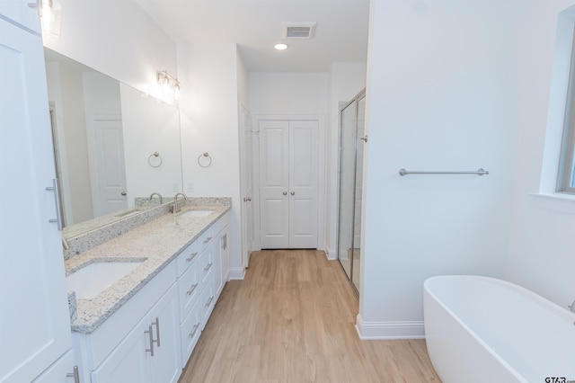 bathroom with hardwood / wood-style floors, vanity, and independent shower and bath