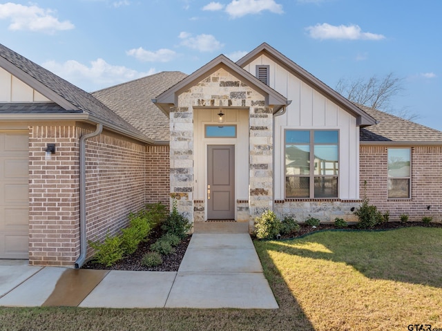 view of exterior entry with a lawn and a garage