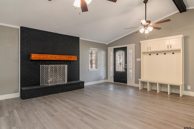 interior space featuring ceiling fan, crown molding, light hardwood / wood-style floors, lofted ceiling, and a fireplace