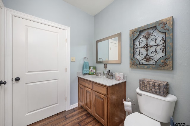 bathroom with toilet, vanity, and hardwood / wood-style flooring