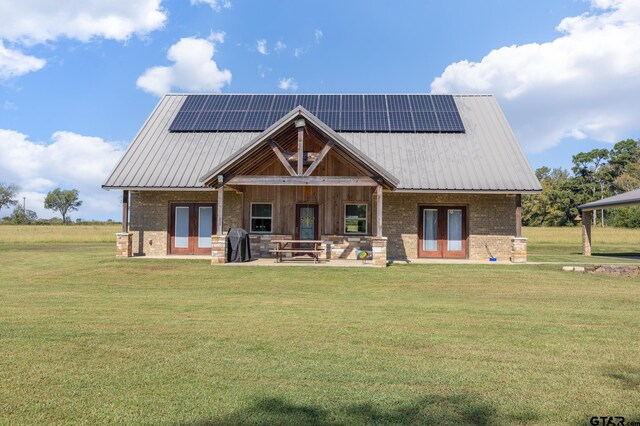 rear view of property featuring a patio, solar panels, and a lawn